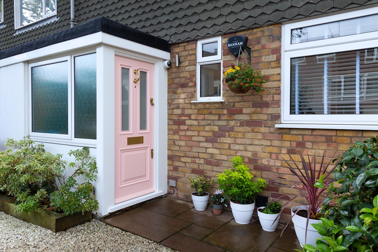Front of House With Pink Banham Door with Brass Door Locks, Letter Plate, Doctor's Door Knocker, Eye View, as well as Black Banham Intruder Alarm Bellbox and White Dome CCTV